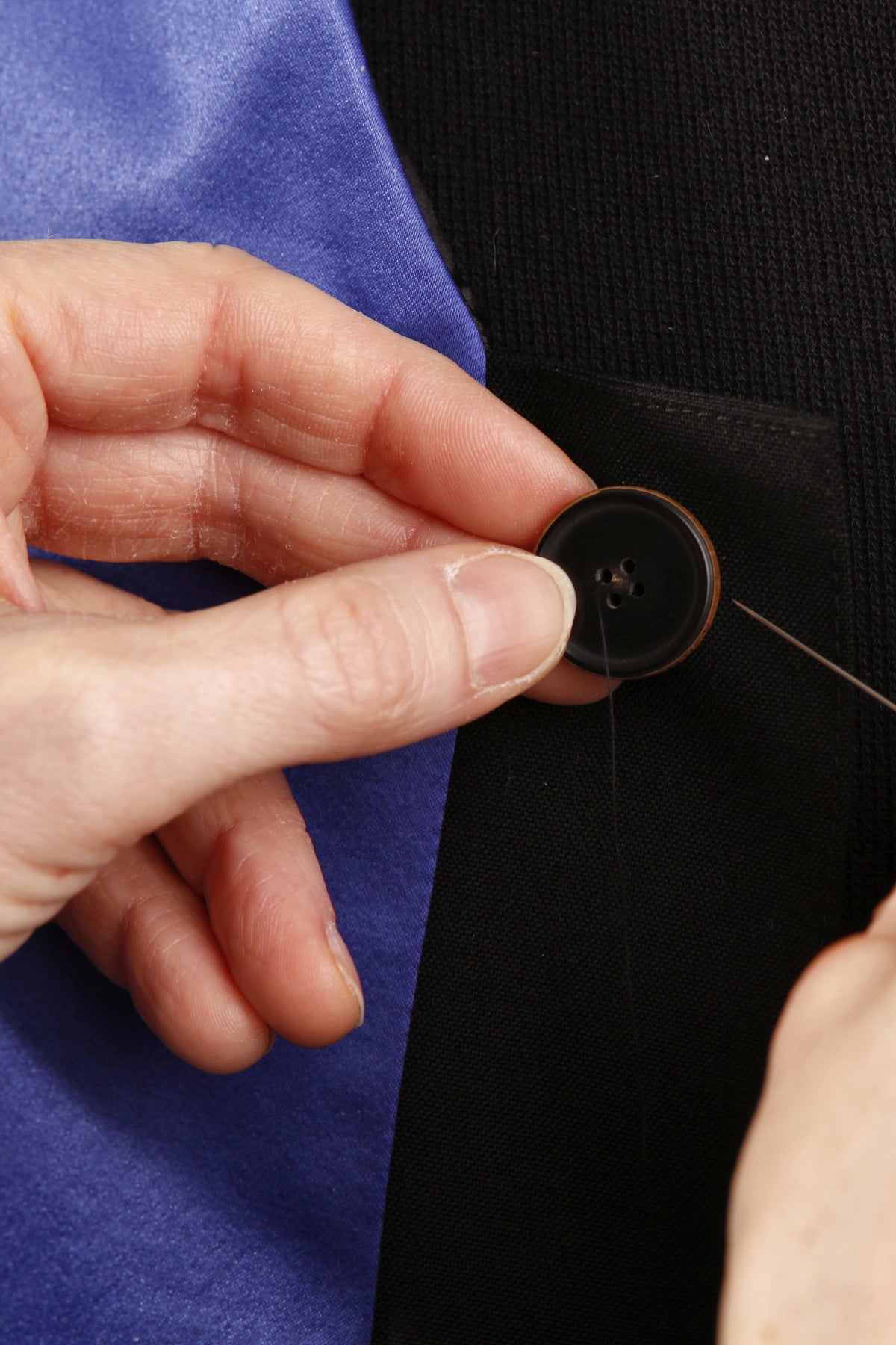 Handarbeit im Atelier: ein Knopf wird von Hand angenäht
