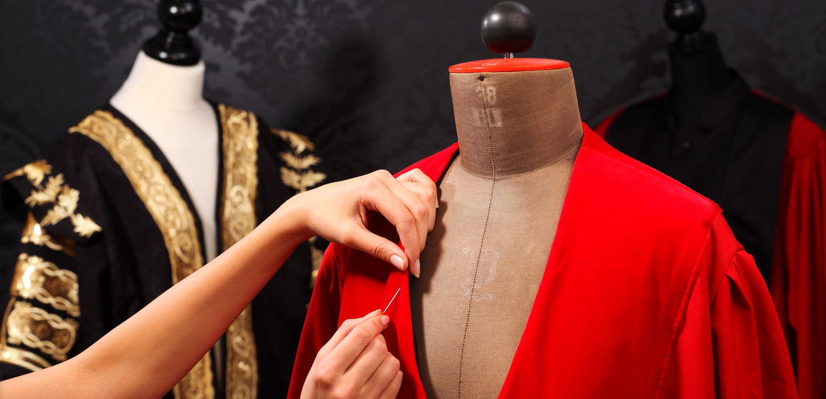 Eine rote Robe wird im Atelier an der Büste abgesteckt